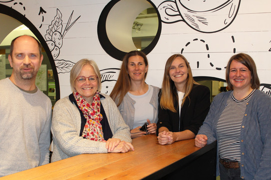 Teamfoto: 5 Personen stehen um einen Stehtisch herum und lächeln in die Kamera (v.l.n.r.): Carsten Bender, Anne Haage, Rose Jokic, Sabrina Januzik und Anne Pferdekämper-Schmidt