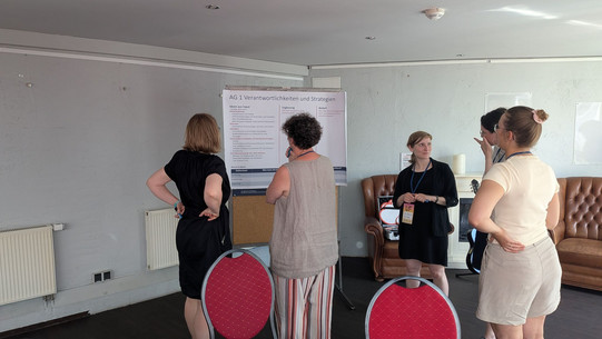 Foto: Teilnehmende stehen vor einem Flipchart und tauschen sich aus.